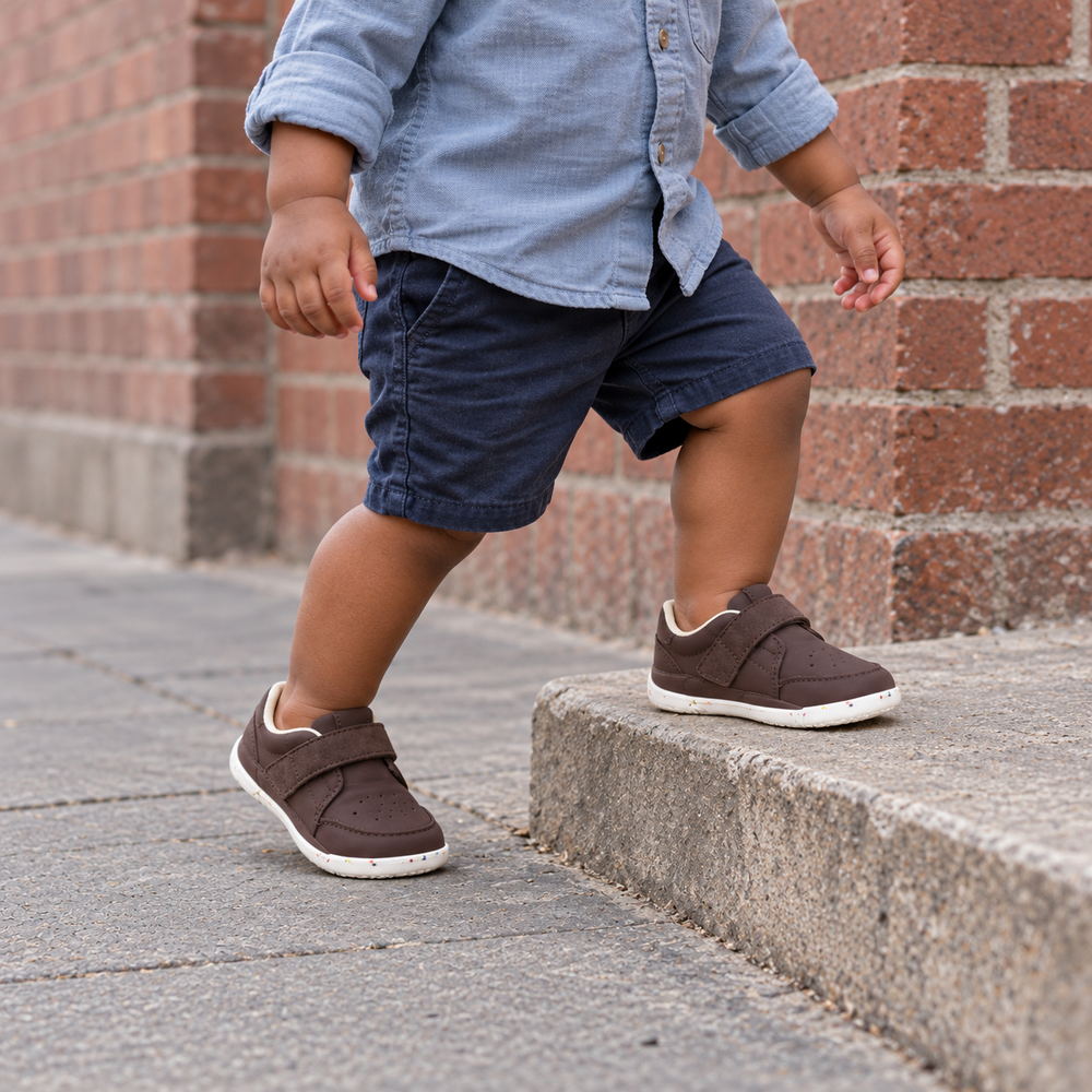 A child wearing chocolate Pedibare perforated PU shoes outdoors